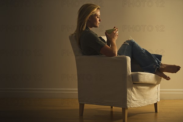 Woman sitting in armchair. Photo : Daniel Grill