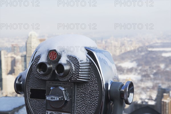 USA, New York City, Coin operated binoculars covered with snow, Central Park in background. Photo : fotog