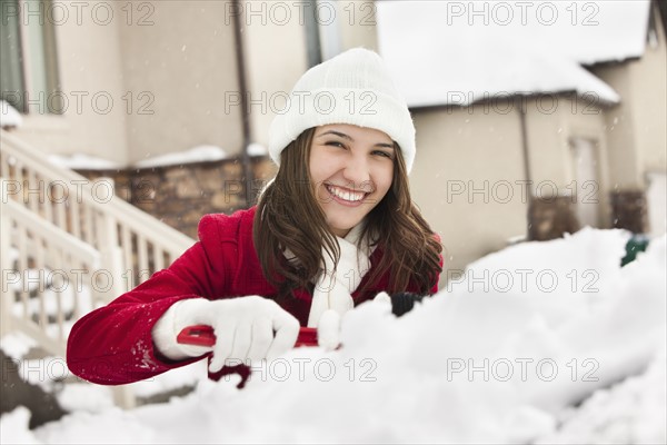 USA, Utah, Lehi, Portrait of young woman scraping snow from car. Photo : Mike Kemp