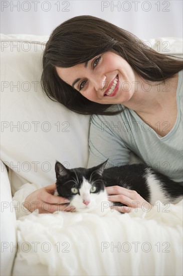 Portrait of woman with cat on sofa.