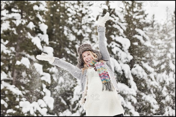 USA, Utah, Salt Lake City, young woman in winter clothing throwing snow in air. Photo : Mike Kemp