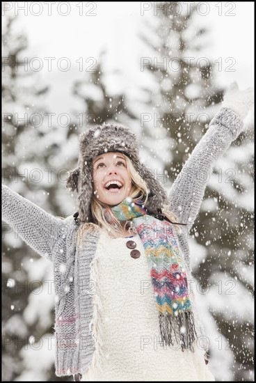 USA, Utah, Salt Lake City, young woman in winter clothing throwing snow in air. Photo : Mike Kemp