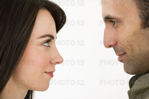 Studio profile of couple looking in eyes face to face.