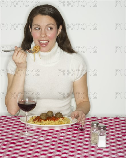Portrait of woman eating spaghetti with meatballs.