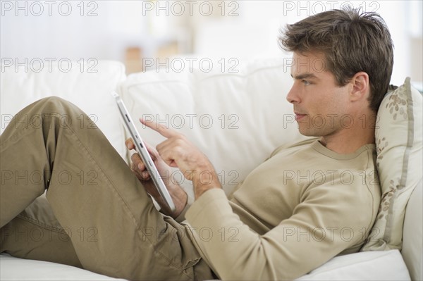 Man sitting on sofa, using digital tablet.