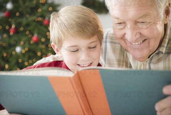 Grandfather and grandson (8-9) reading book. Photo : Jamie Grill Photography