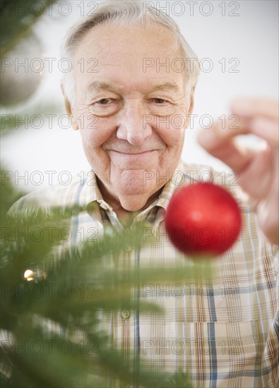 Portrait of senior man decorating Christmas tree. Photo : Jamie Grill Photography