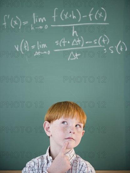 Boy (8-9) calculating equation by blackboard. Photo : Jamie Grill Photography