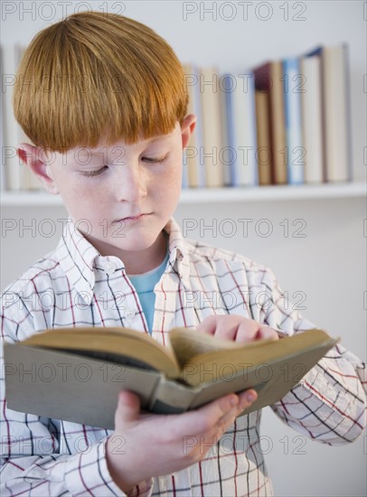 Boy (8-9) reading book. Photo : Jamie Grill Photography