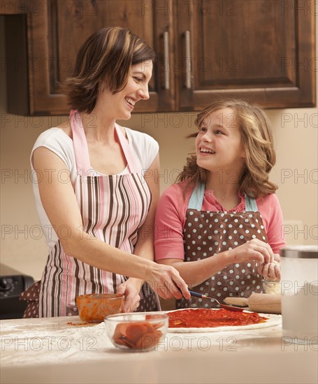 Mother and daughter (10-11) preparing pizza in kitchen. Photo : Mike Kemp