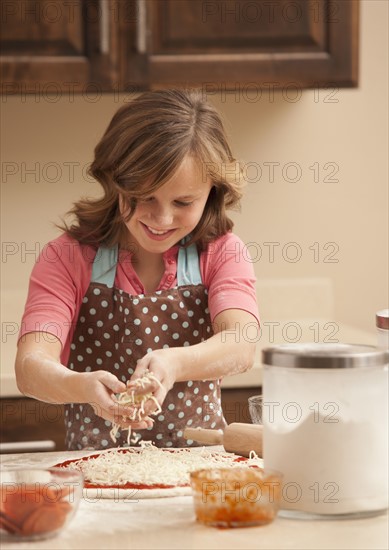 Girl (10-11) preparing pizza in kitchen. Photo : Mike Kemp