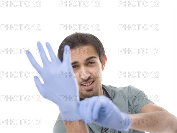 Young surgeon putting on protective gloves. Photo : Dan Bannister