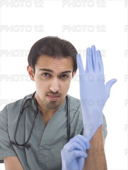 Young surgeon putting on protective gloves. Photo : Dan Bannister