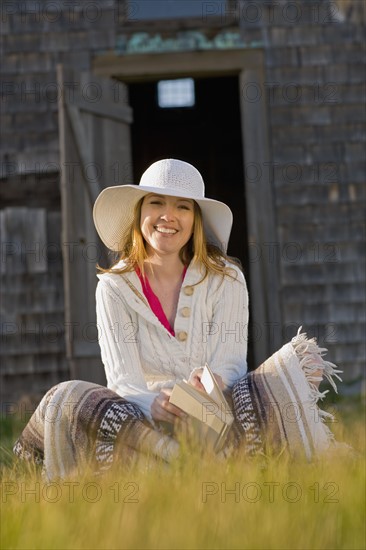 USA, California, Bolinas, Portrait of young woman reading book outdoors. Photo : Noah Clayton