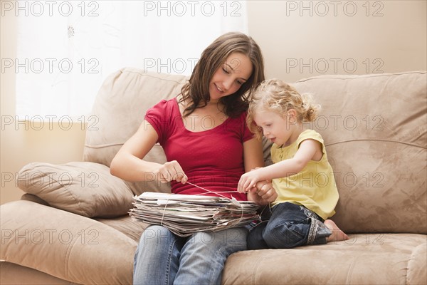 Young woman with sister (2-3) tying newspapers for recycling. Photo : Mike Kemp