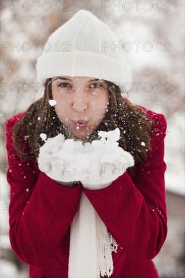 USA, Utah, Lehi, Portrait of young woman blowing snow. Photo : Mike Kemp