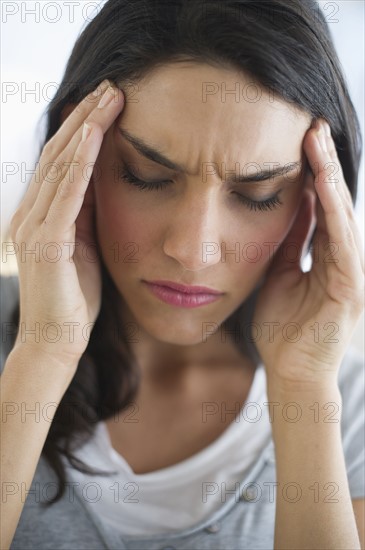 Woman suffering from headache holding head in hands.