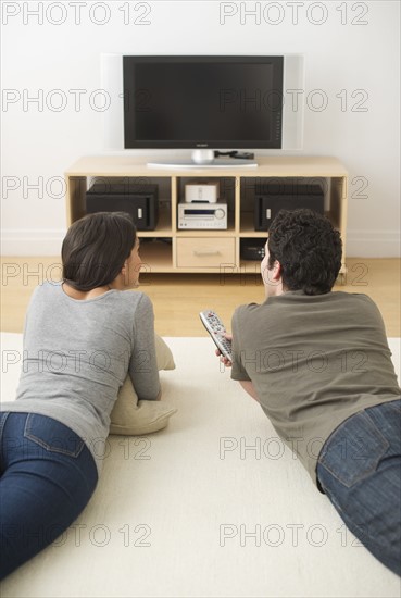 Couple lying on floor watching tv.