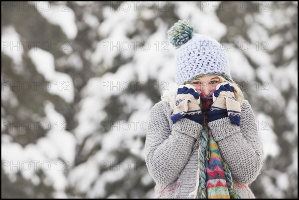 USA, Utah, Salt Lake City, portrait of young woman in winter clothing covering mouth. Photo : Mike Kemp
