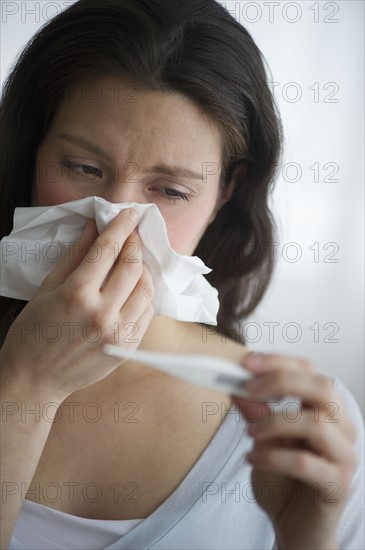 Woman with flu blowing nose.