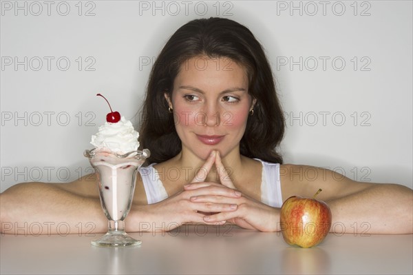 Woman choosing between ice cream and apple.