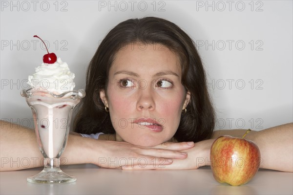 Woman choosing between ice cream and apple.