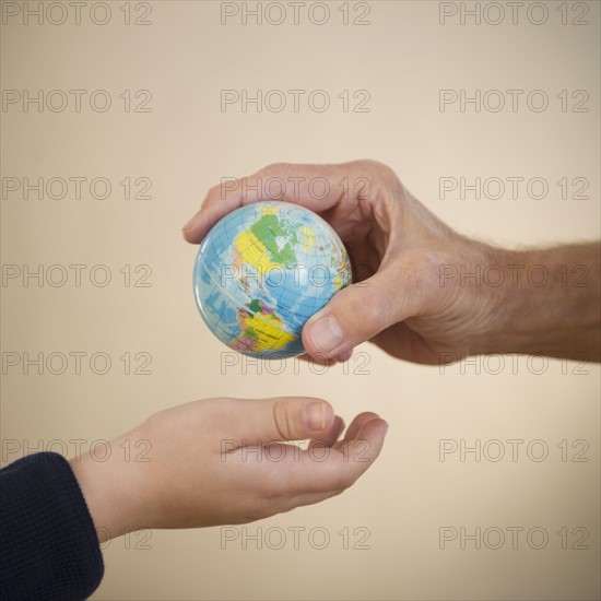 Close up of hands of grandfather and grandson (8-9) with small globe. Photo : Jamie Grill Photography