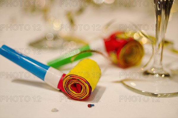 Party horn blower and champagne flute on table, close-up.