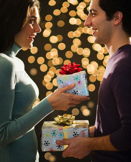 Young couple giving Christmas presents each other. Photo : Daniel Grill