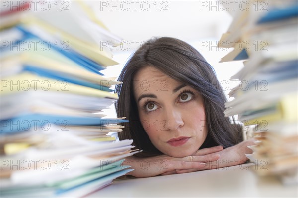 Young woman looking at stack of documents at desk.