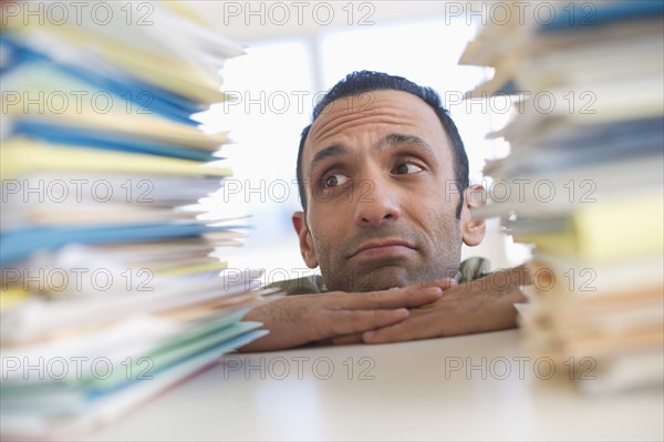 Young woman looking at stack of documents at desk.