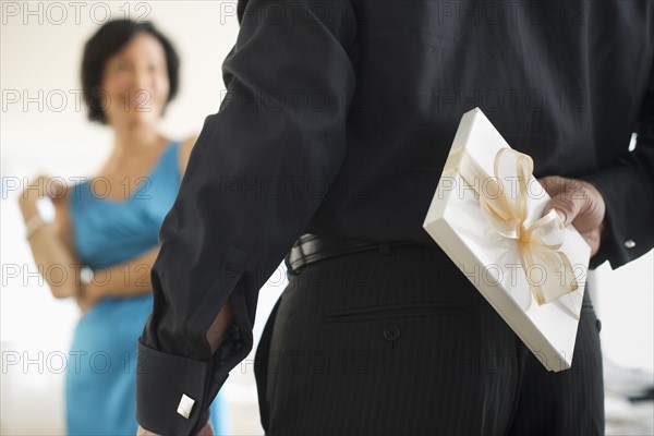 Man hiding gift box behind his back.