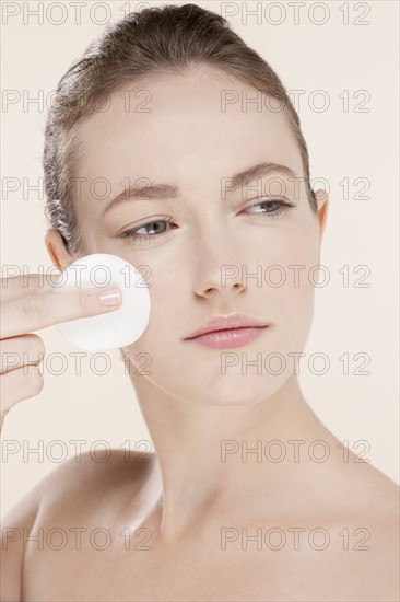 Portrait of young woman holding cotton pad. Photo : Jan Scherders