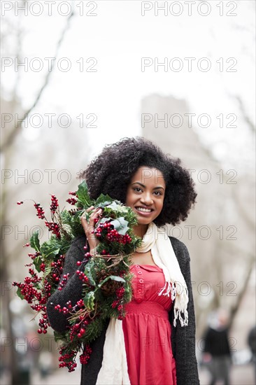 USA, Washington State, Seattle, Cheerful young woman holding christmas wreath. Photo : Take A Pix Media
