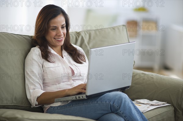 Woman sitting on sofa and using laptop.