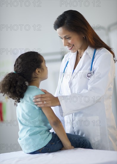 Female pediatrician examining girl (6-7) in doctor's office.