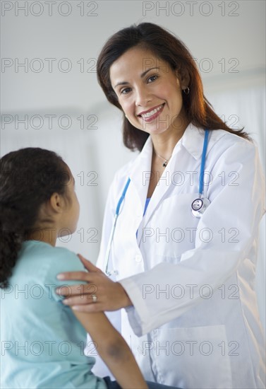 Female pediatrician examining girl (6-7) in doctor's office.