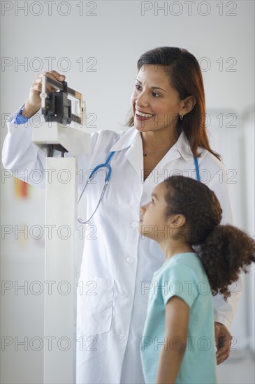 Female pediatrician examining girl (6-7) in doctor's office.