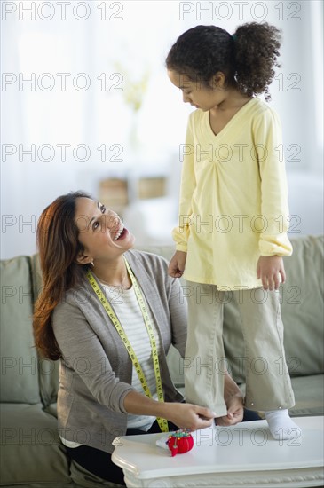 Mother preparing daughter's (6-7) clothing.