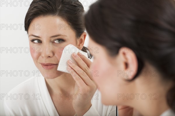 Woman removing make-up in bathroom.