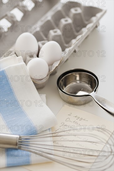 Studio shot of eggs, egg whisk and recipe.