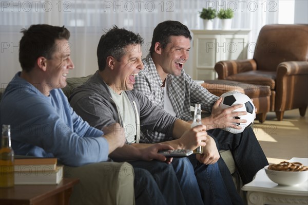 Three men watching television.