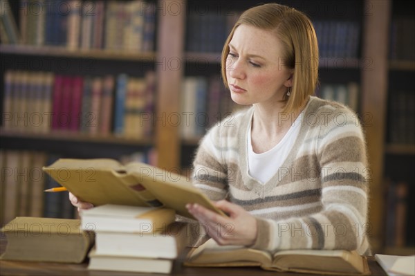 Woman reading book in library.