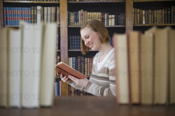 Woman reading book in library.