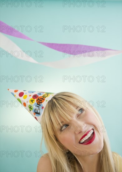 Young woman wearing party hat laughing. Photo : Jamie Grill Photography