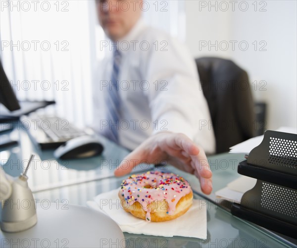 Businessman reaching for donut. Photo : Jamie Grill Photography