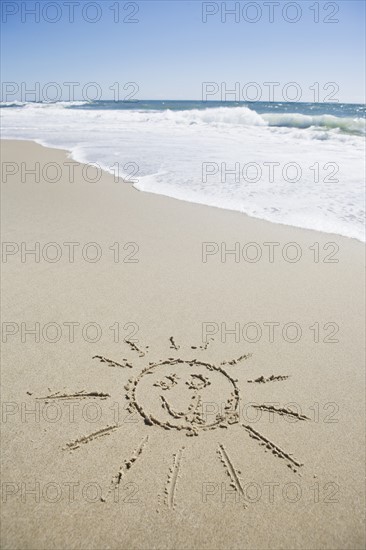 USA, Massachusetts, Sun face drawn on sandy beach. Photo : Chris Hackett