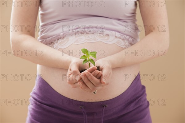 Young pregnant woman holding young plant. Photo: Mike Kemp