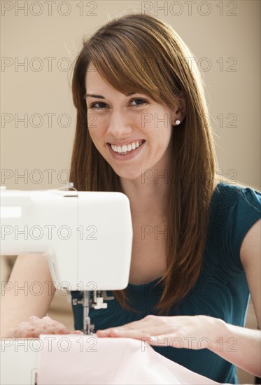 Portrait of smiling young woman using sewing machine. Photo: Mike Kemp