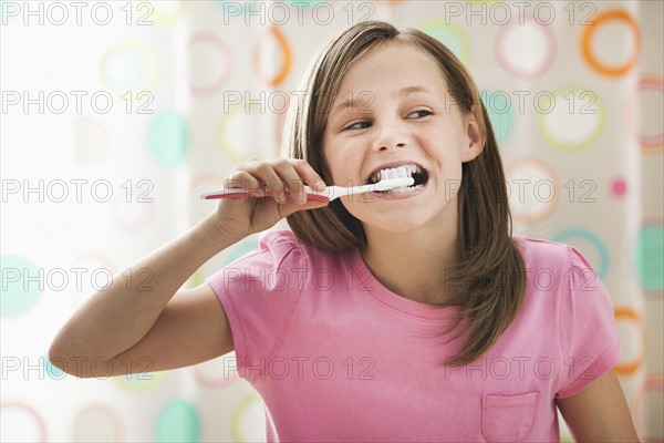 Girl (10-11) brushing teeth. Photo : Mike Kemp